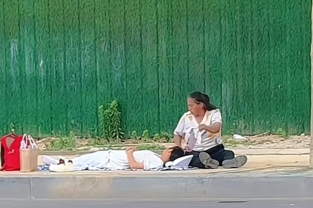 高考生躺路边午休 家长在旁扇扇子 